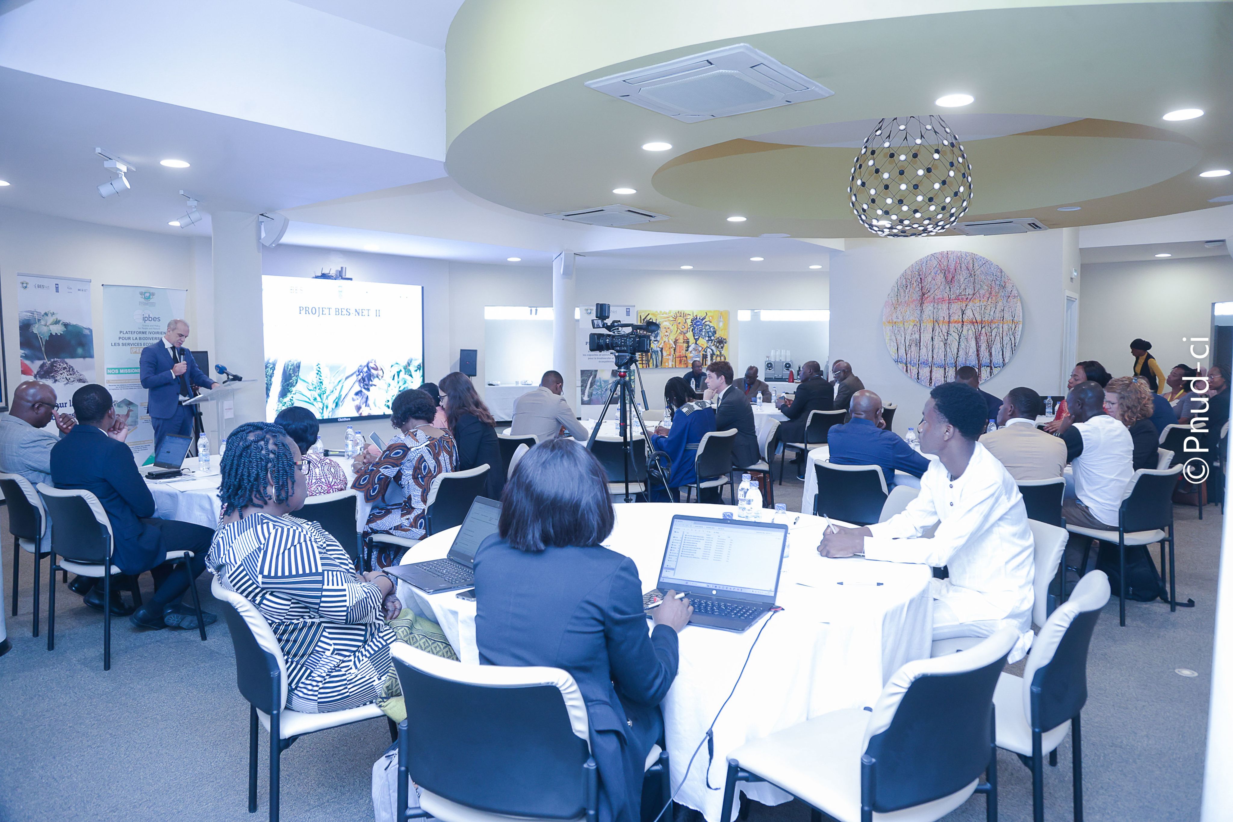 A group of participants at the West and Central Africa Regional Trialogue event gathered in a lush forest, attentively listening to a speaker. 