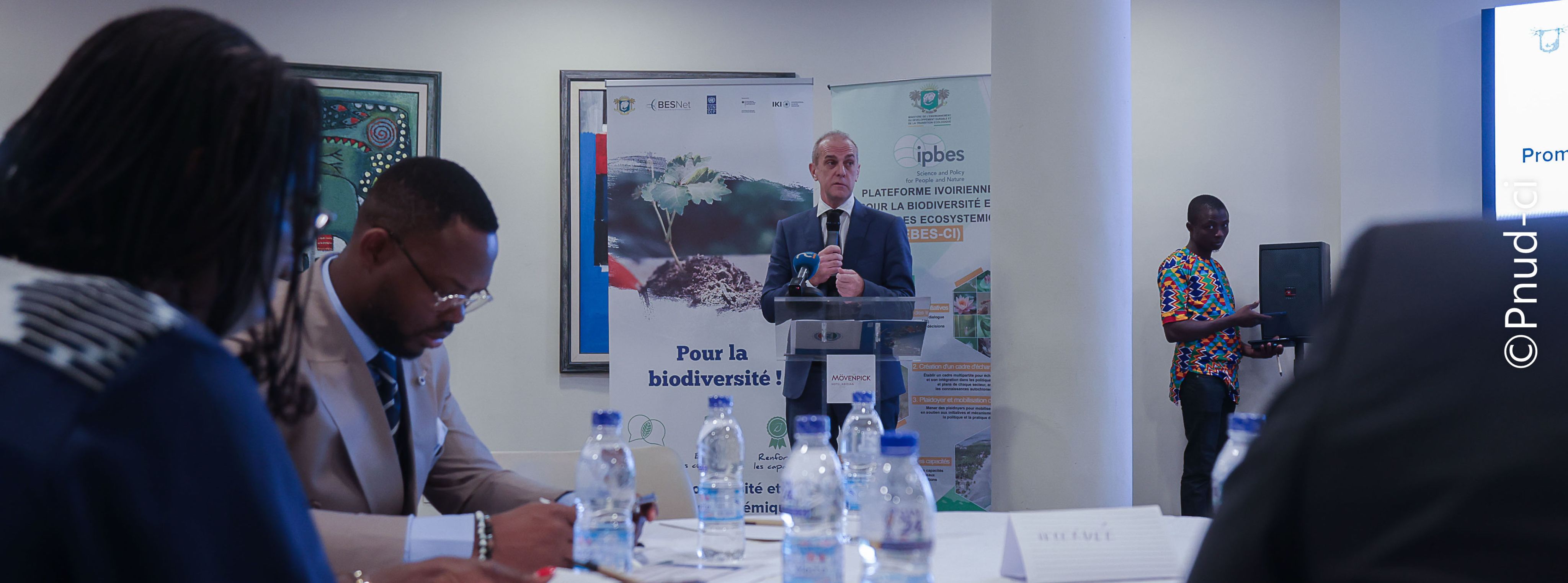 A group of participants at the West and Central Africa Regional Trialogue event attentively observing something in a forest setting. 