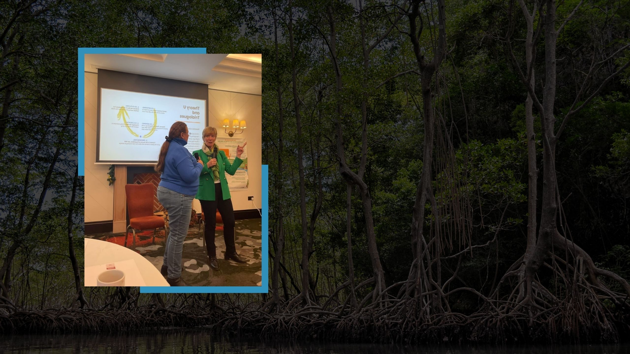 Aleyda Capella, wearing a blue sweater, speaking with another woman in a green blazer during a discussion on Theory U and Trialogues, with a presentation slide visible in the background