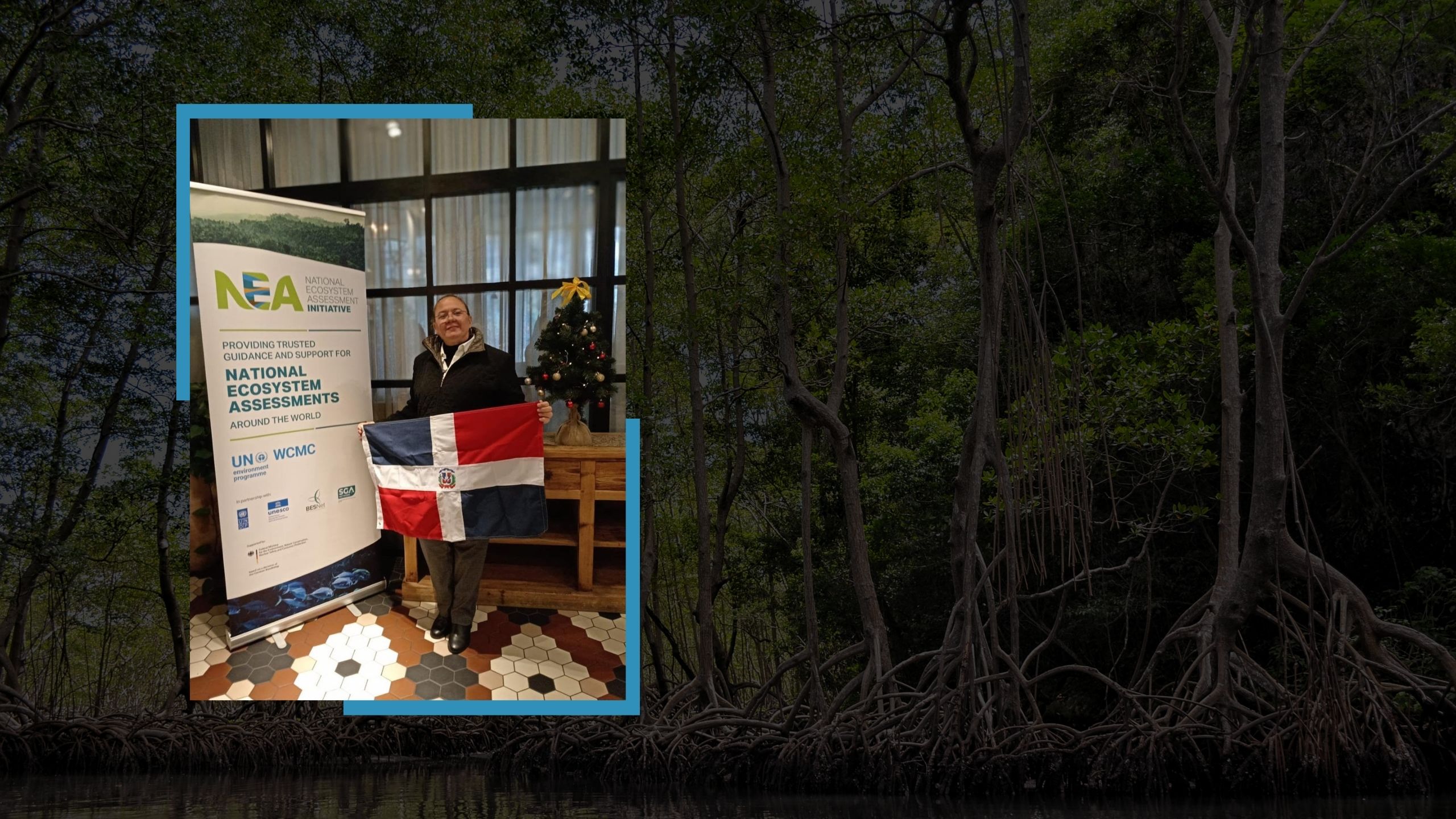 Aleyda Capella holding the Dominican Republic flag next to a National Ecosystem Assessments (NEA) banner at an indoor event.