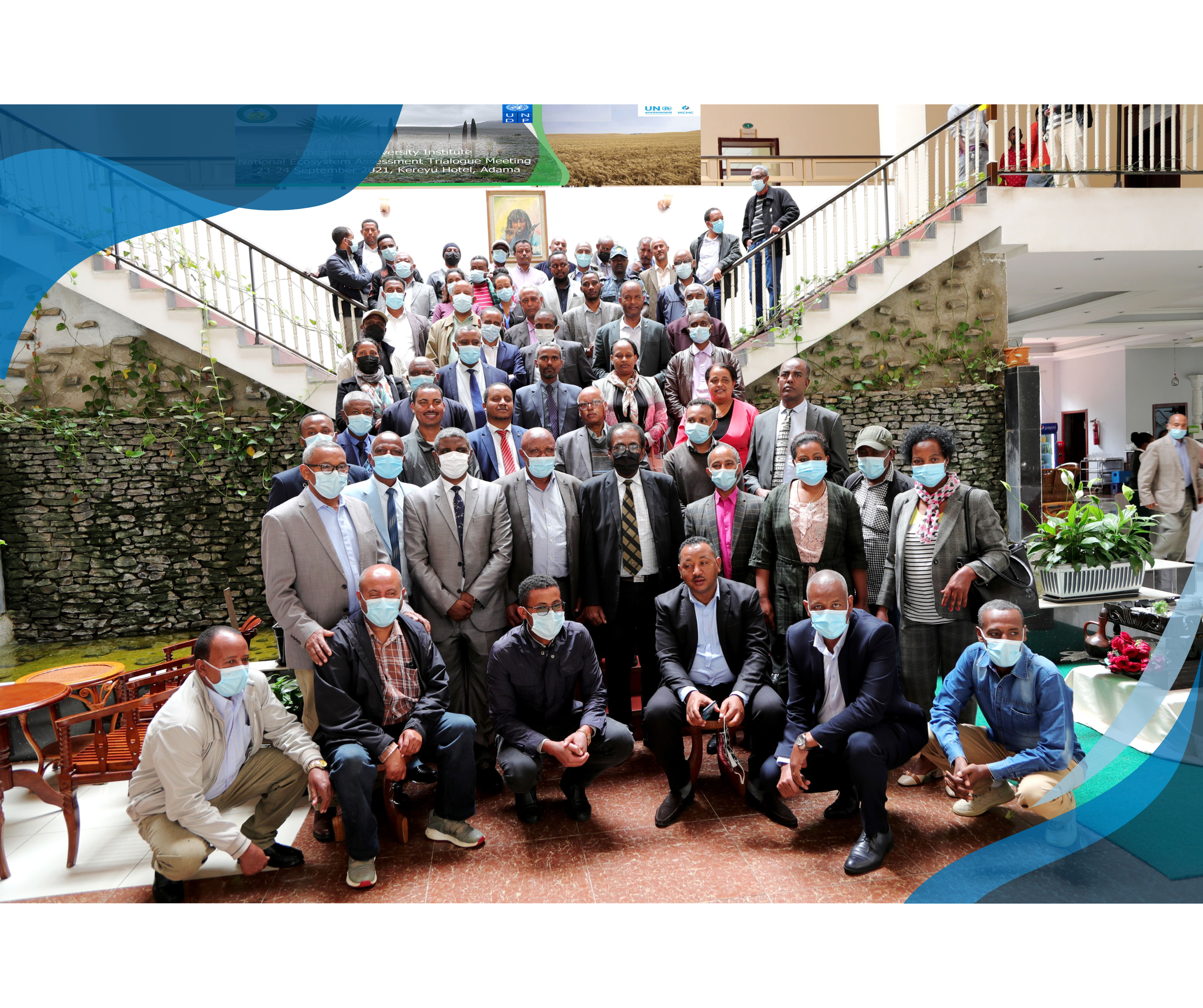 A large group of people, many wearing face masks, gathered indoors on the stairs and landing for a group photo, under a banner for the Ethiopian Biodiversity Institute's National Ecosystem Assessment Dialogue Meeting.