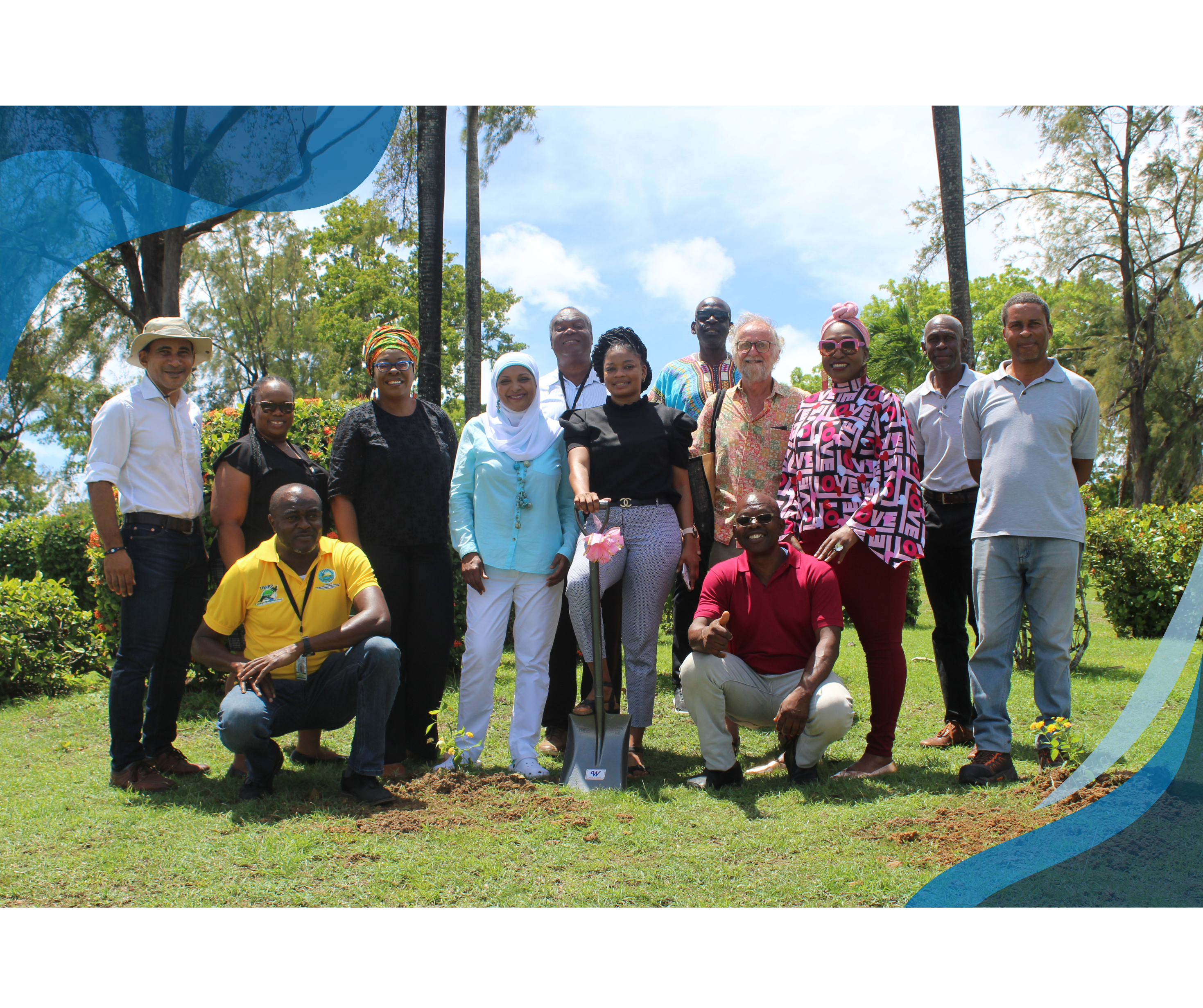 A group photo of people smiling and posing outdoors, some standing and some kneeling, with a tree planting activity in progress.