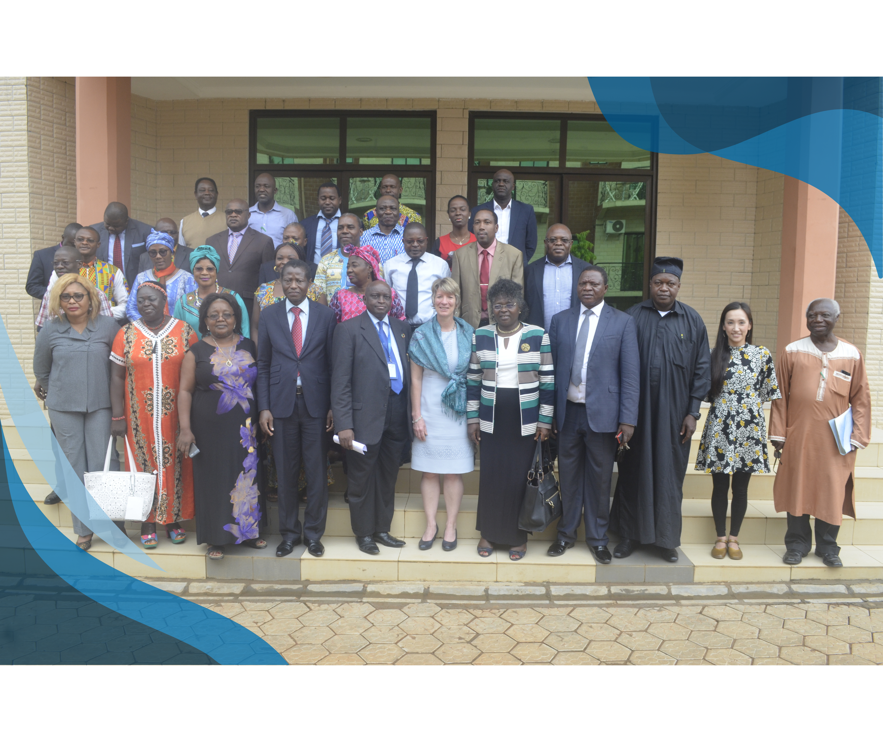 A group of diverse professionals, dressed in formal and traditional attire, standing on the steps of a building, posing for a group photo.