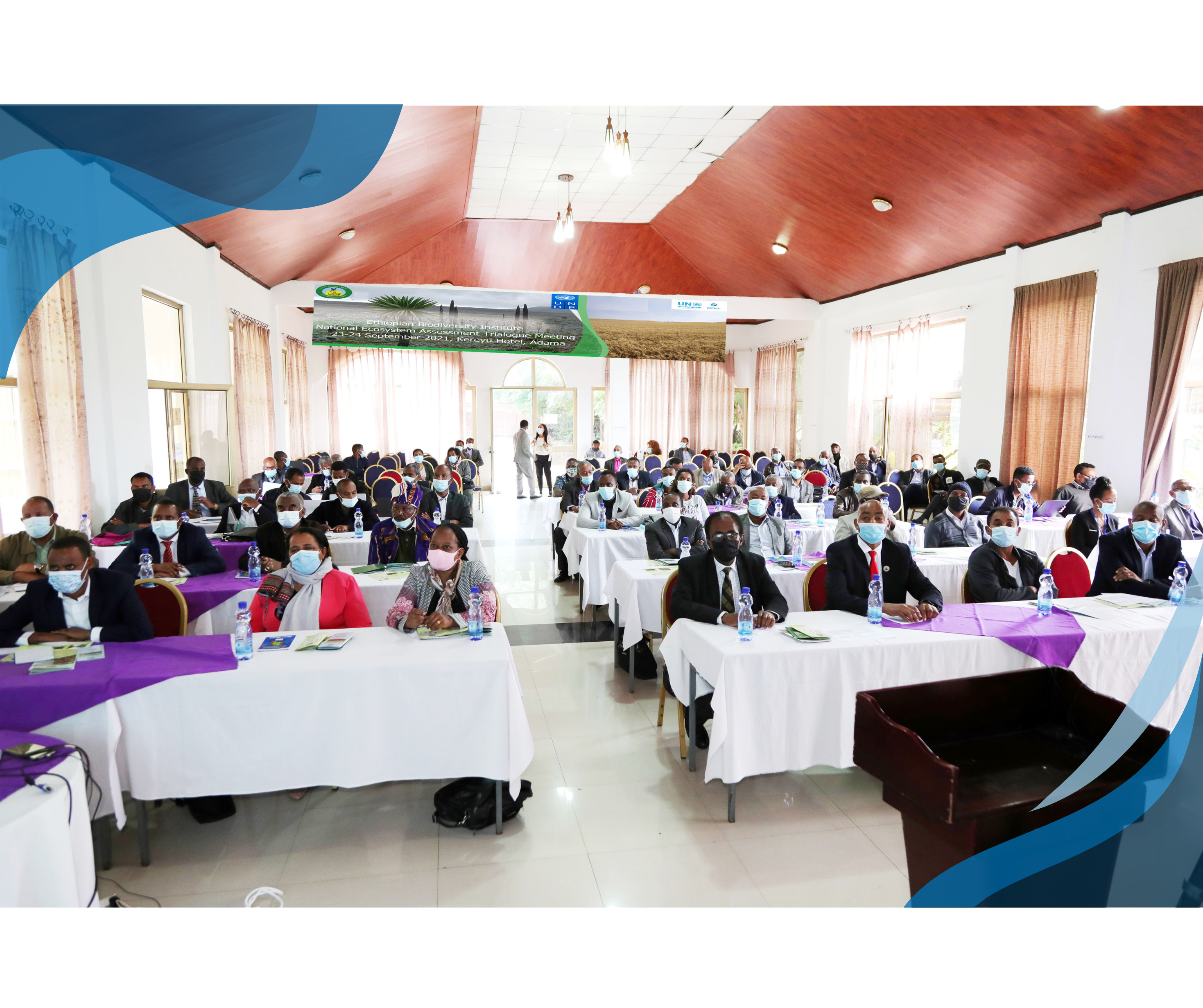 A wide view of a conference hall filled with participants sitting at tables with purple and white tablecloths, attending a plenary session at the Ethiopian Biodiversity Institute's National Ecosystem Assessment Dialogue Meeting.