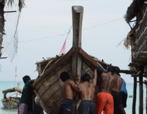 A group of fisherfolks pushing a boat towards the sea