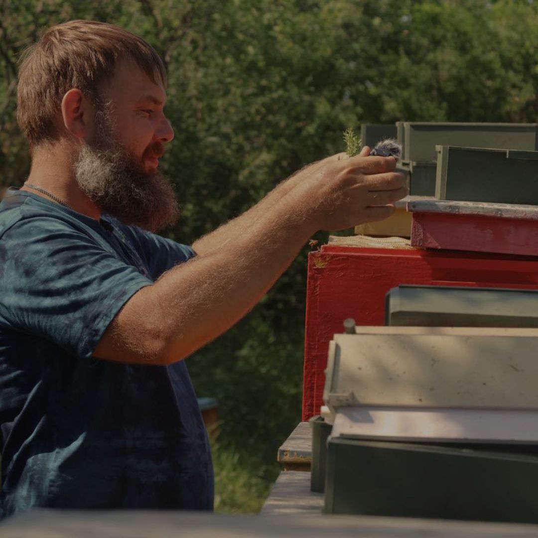 A man working outdoors with a beehive
